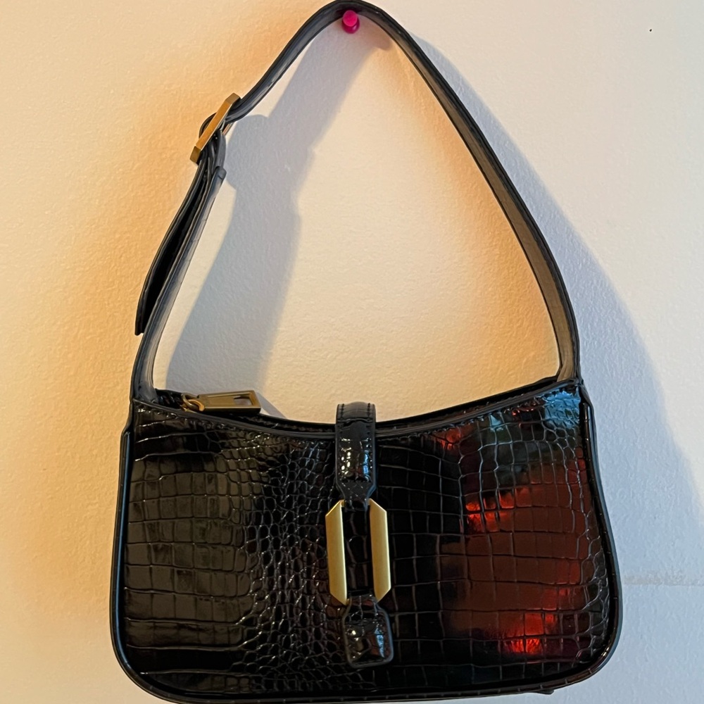 black leather shoulder bag with gold buckle and zipper closure.